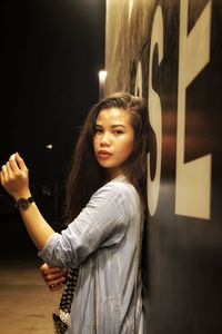 Portrait of young woman standing against wall