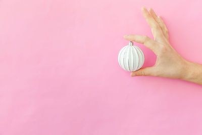 Close-up of hand holding pink over colored background