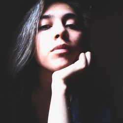 Close-up portrait of a young woman over black background