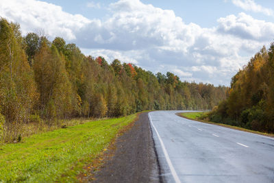 Road amidst trees and plants against sky