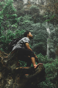 Young man sitting on rock in forest