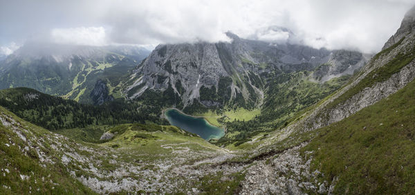 Scenic view of lake and rocky mountains against cloudy sky