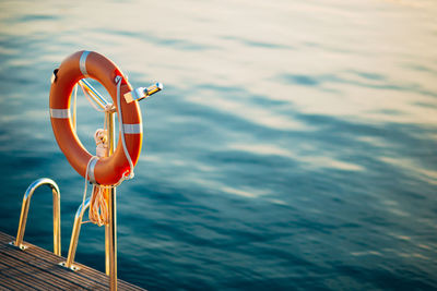 Wheel by sea against orange sky