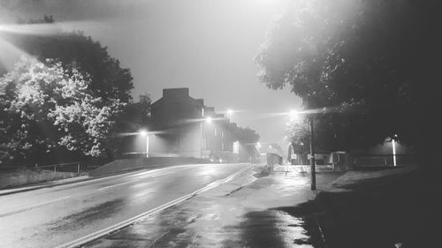 Road by trees against sky at night