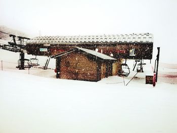 House on snow covered field against sky