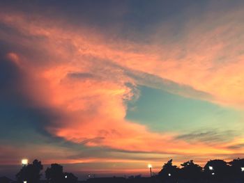 Silhouette trees against dramatic sky during sunset