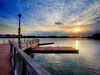 Pier in sea at sunset