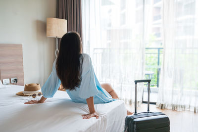 Rear view of woman using mobile phone at home