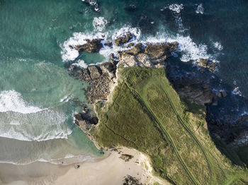 An aerial view of a headland jutting out into the sea.