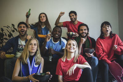 Portrait of multi-ethnic friends watching soccer match while sitting at home