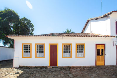 Exterior of house by building against clear blue sky