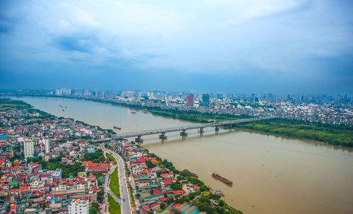 High angle view of city by river against sky