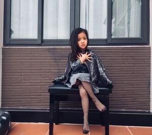 Portrait of woman sitting on seat against window