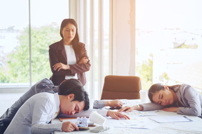 Angry businesswoman looking at colleagues sleeping at conference table