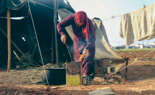 A woman cooks food on wood in a syrian refugee camp.