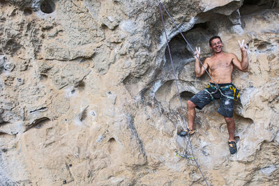 Man smiling for the photographer while climbing on rock face in china