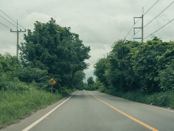 Road amidst trees against sky