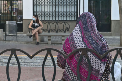 Woman with bicycle on railing in city