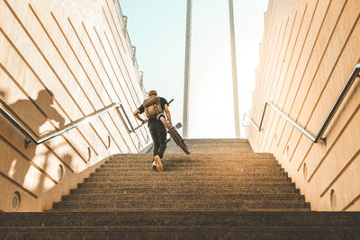 Low angle view of young man carrying bicycle while moving up on steps