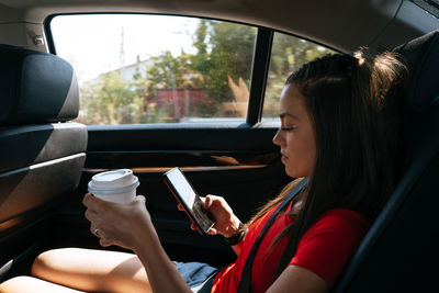 Side view of woman using mobile phone while sitting in car