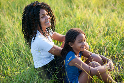 Smiling sisters sitting on grass