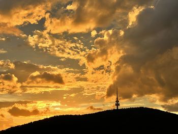 Silhouette of tower against dramatic sky during sunset