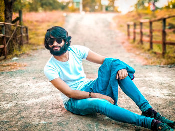 Young man looking away while sitting outdoors