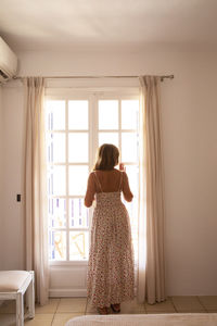 Rear view of woman looking through window