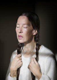Young woman looking away against black background