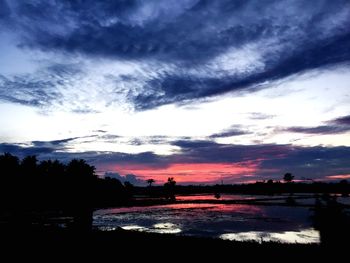 Silhouette of trees against cloudy sky