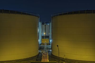 Yellow oil tanks at factory against clear sky at night