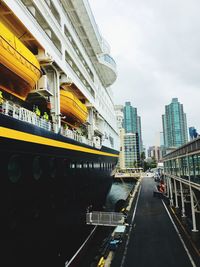 Road by buildings against sky in city
