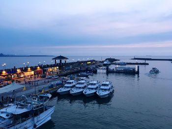 Boats moored at harbor during sunset