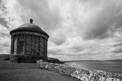 Lighthouse by sea against sky