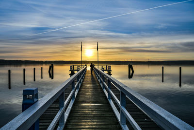 Pier over lake against sky during sunset