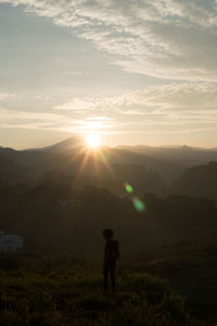 Man standing on field against sky during sunset