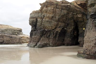 Rock formation on beach against sky