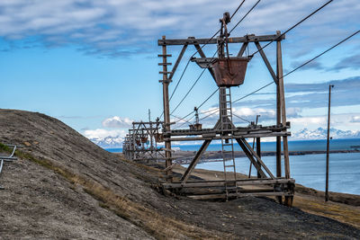 Electricity pylon by sea against sky