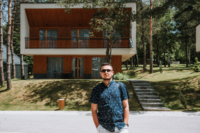 Portrait of young man standing against building