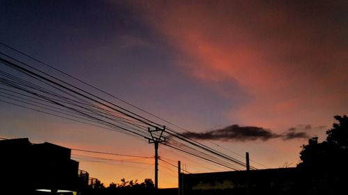 Low angle view of silhouette electricity pylon against sky during sunset
