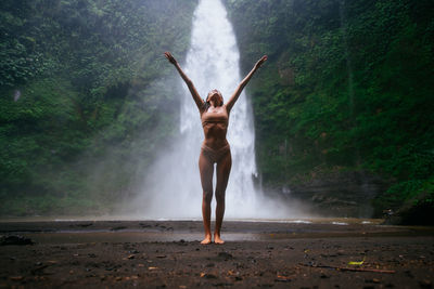 Young woman standing against waterfall