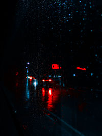 Illuminated city street seen through wet window at night