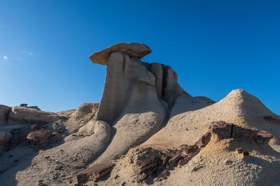 Bisti badlands landscape of dramatic grey hoodoos or caprock formations against blue sky 