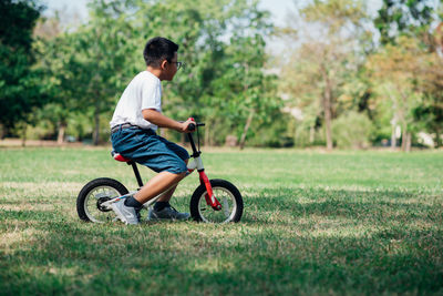 Side view of boy riding bicycle on grass