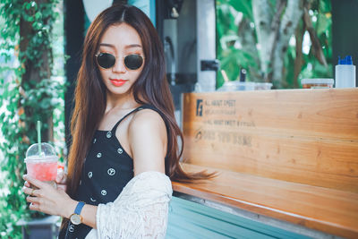 Young woman holding drink standing outdoors