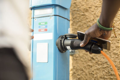 Midsection of man plugging in electric cable for charging at station