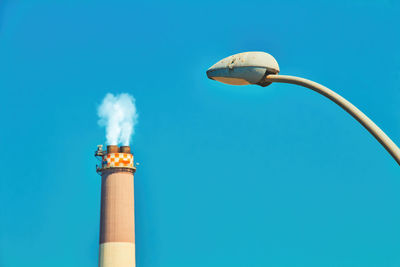 Low angle view of smoke stack against blue sky