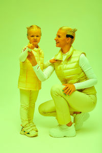 Side view of mother and daughter against white background