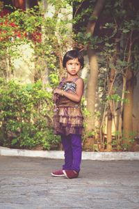 Portrait of cute girl standing against plants