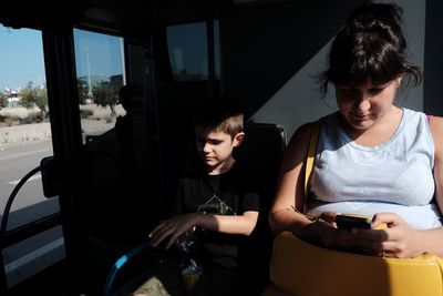 Young woman using mobile phone while sitting in bus